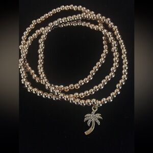 Three Gold Stretch Beaded Bracelets-one with a crystal Palm Tree Charm. Fits all